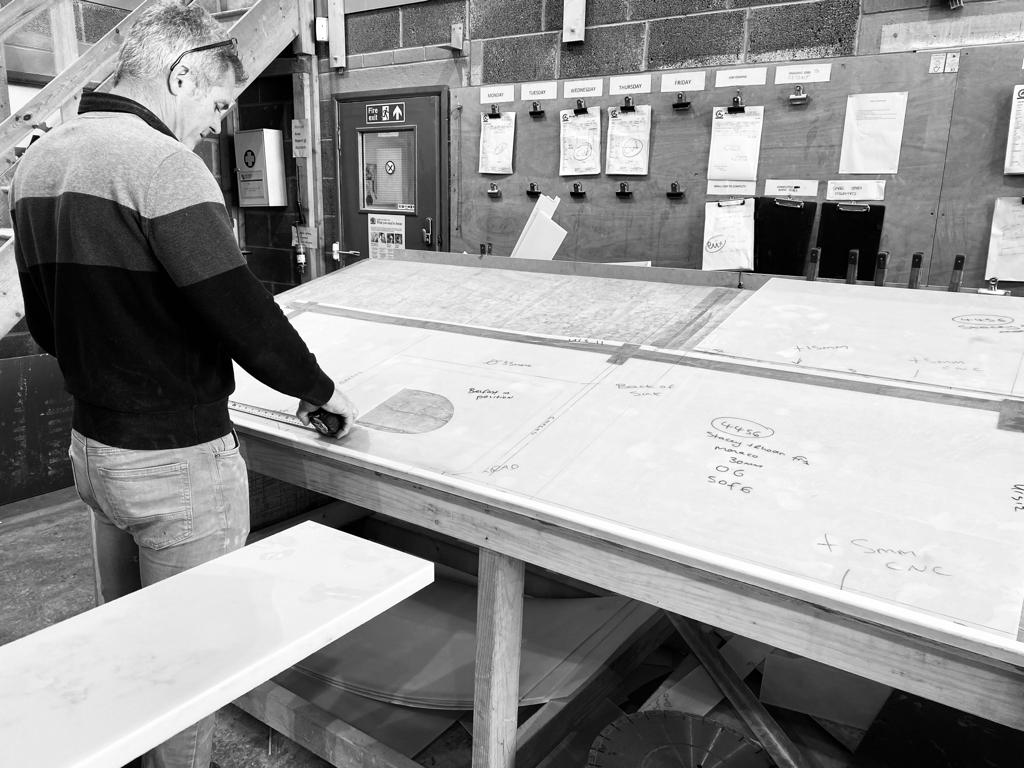 Craftsperson measuring and marking stone slab templates in the Amaris workshop